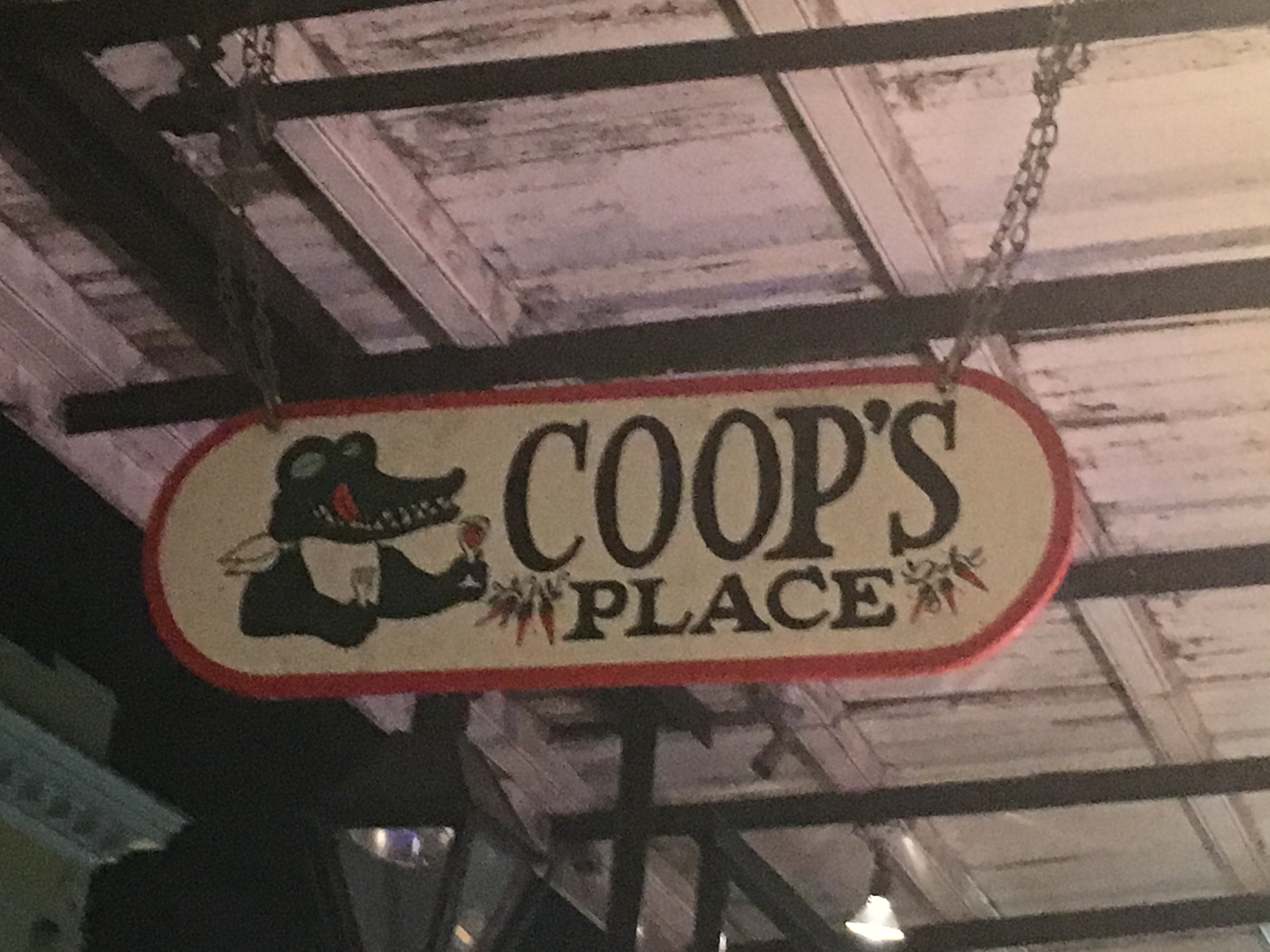 Red and green sign reading Coops Place for food and drink in New Orleans