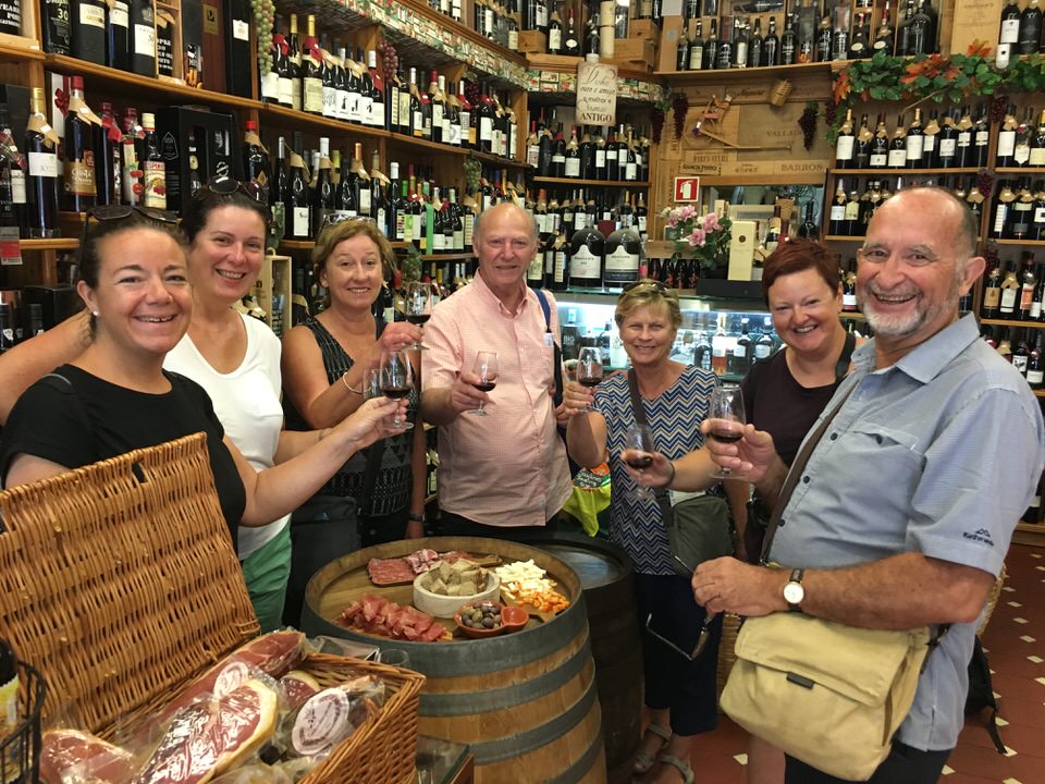 the tour group with a glass of port standing around barrels with meat and cheese